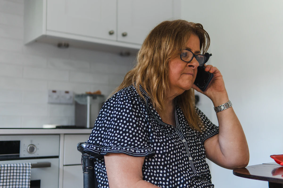 A woman talking on the phone in her kitchen.