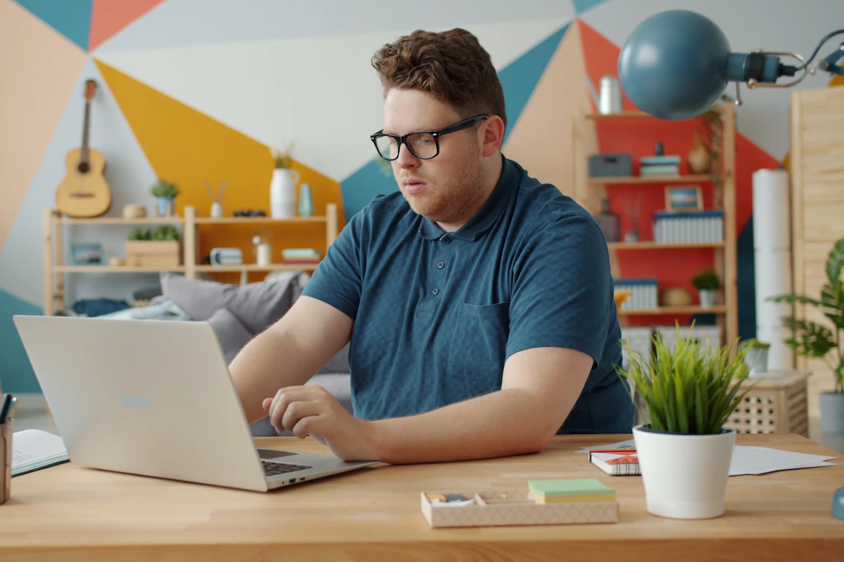 A man checking information on a laptop at his desk at home.