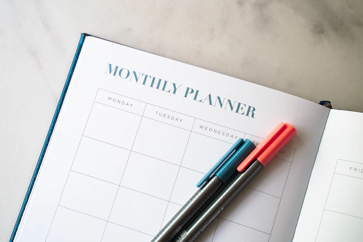 An open monthly planner with two pens.