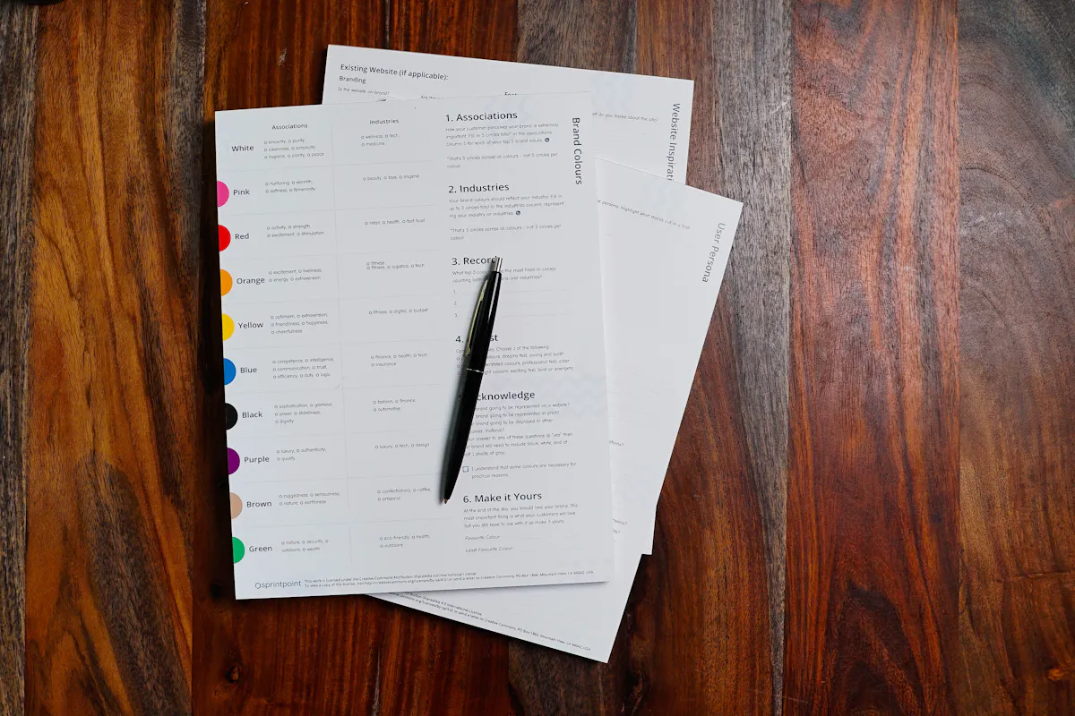 A stack of paper forms and a pen on a wooden table.